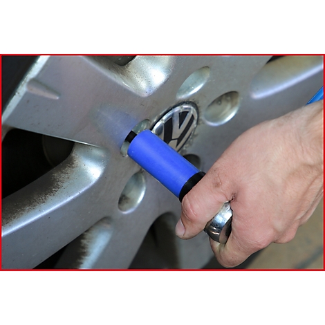 Nahaufnahme eines silbernen Autorads, an dem eine blaue Steckschlüssel-Nuss angebracht wird. Im Hintergrund ist das VW-Logo zu sehen.